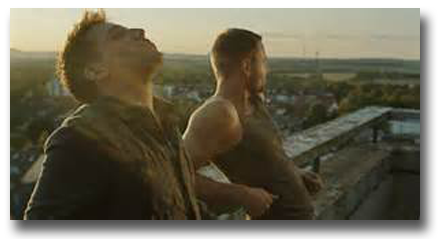 Movie still from Free Fall of two men standing on balcony overlooking city below