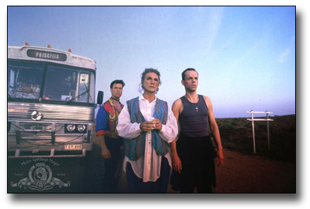 Scene from Priscilla Queen of the Desert standing in front of the bus looking off into the vast Australian outback.